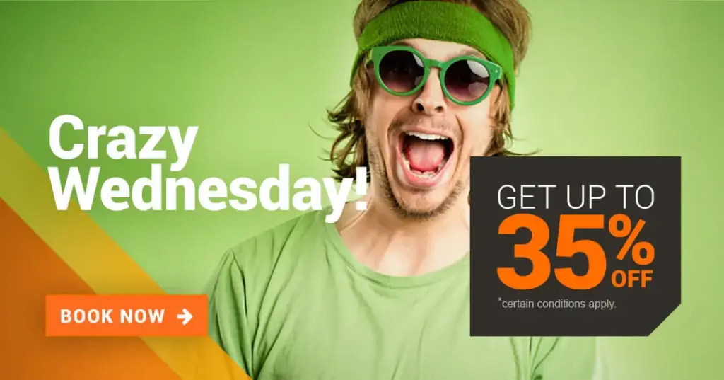 A man with green glasses in a green setting, his mouth is wide open